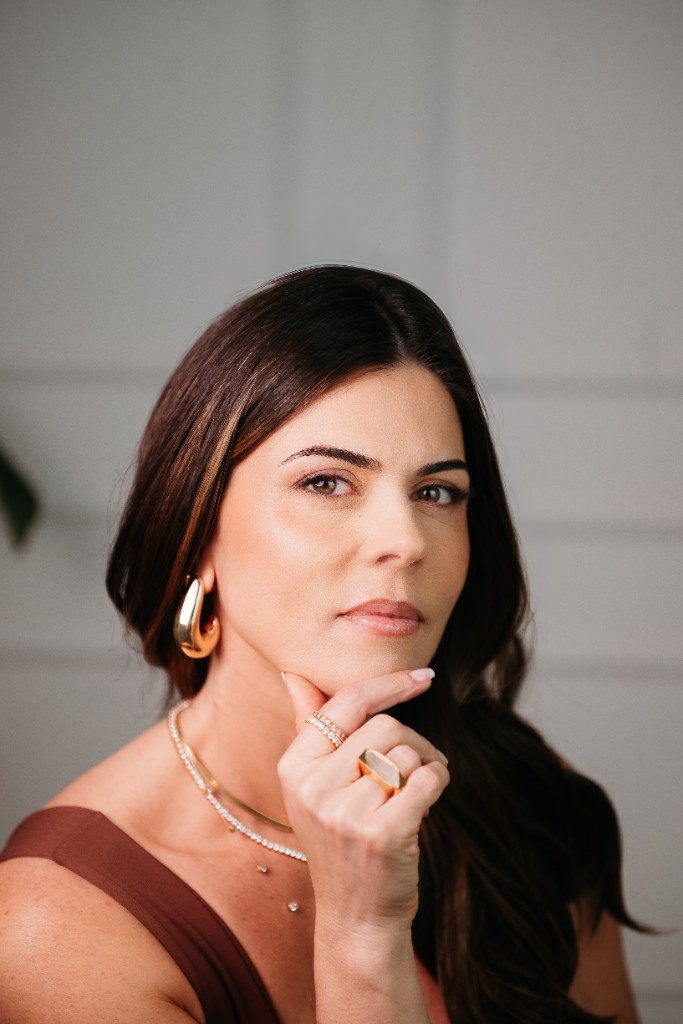 A Lise usando brinco gota dourado, anéis e colar riviera