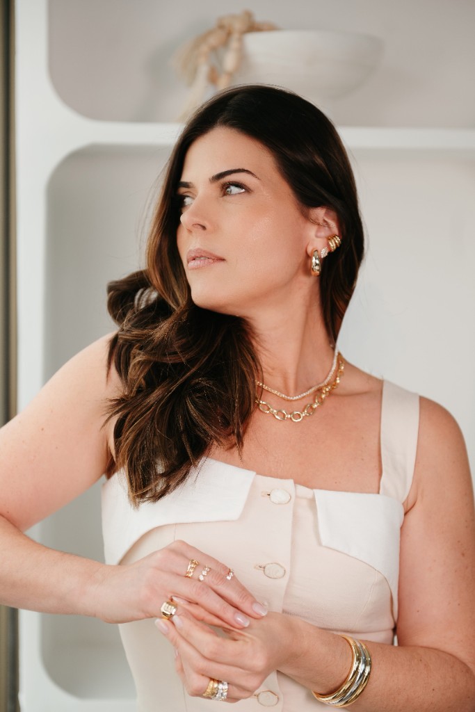 A Lise de perfil com brincos e colares dourados